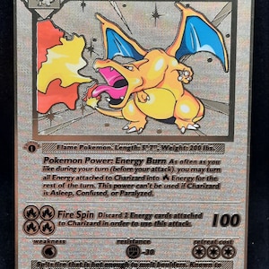Peut inclure: Carte de collection Charizard avec une finition argentée holographique. Elle présente une illustration de Charizard, un Pokémon de type feu, avec le texte "Charizard" et "120 HP". La carte mesure 14.5 cm de long et pèse 90.7 kg.
