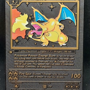 May include: A gold Pokemon trading card featuring Charizard, a fire-type Pokemon. The card has a black background with gold accents. The card text reads "Charizard, 120 HP, Flame Pokemon, Length: 5'7", Weight: 200 lbs. Pokemon Power: Energy Burn. Fire Spin. Spits fire that is hot enough to melt boulders. Known to unintentionally cause forest fires. LV. 76 #6"