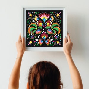 May include: A framed artwork featuring a colorful rooster and floral design. The artwork is in a white frame and has a black background.