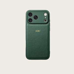 Op de afbeelding: Een donkergroene telefoonhoes met een getextureerde afwerking. De hoes heeft een cameramodule met drie lenzen en een flitser. Goudkleurige initialen "ABC" zijn in het onderste deel van de hoes geëmbosseerd.