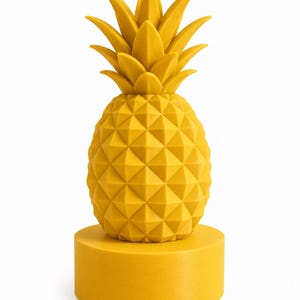 Può includere: Una scultura di ananas giallo brillante caratterizzata da una texture superficiale geometrica e sfaccettata sul corpo del frutto e foglie appuntite sulla sommità. L'ananas è montato su una base cilindrica gialla, liscia e solida, dal look uniforme.