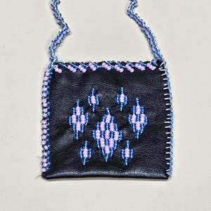 May include: A small, black leather bag with a beaded handle and trim. The bag features a geometric design in shades of blue and lavender. The handle is a wavy design, and the trim is a row of small beads.