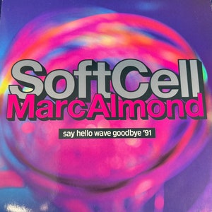 May include: A pink, blue, and purple album cover with the text "Soft Cell Marc Almond say hello wave goodbye '91" in black and silver lettering.