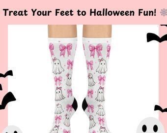 May include: White knee-high socks with a repeating pattern of pink bows and cartoon ghosts. The socks have black heels and toes. Text at the top reads "Treat Your Feet to Halloween Fun!"