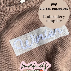Op de afbeelding: Een bruine gebreide trui met een witte rechthoekige stoffen patch waarop het woord winter is geborduurd met lichtblauw garen. De afbeelding bevat de tekst PDF DIGITAL DOWNLOAD Embroidery template en een logo met de tekst mama's MAKES.
