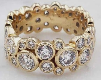 Anillo de eternidad con moissanita engastada en bisel ancho, oro amarillo de 14 k, diamantes redondos dispersos, diseño llamativo de múltiples piedras para bodas.