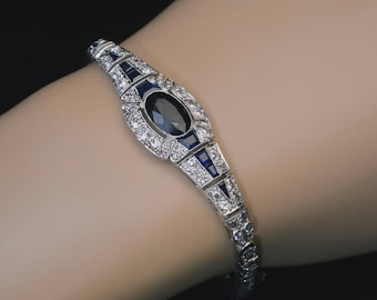 Esta pieza es una clásica pulsera de eslabones estilo "El Gran Gatsby", que presenta un prominente zafiro ovalado y llamativos detalles geométricos azules.