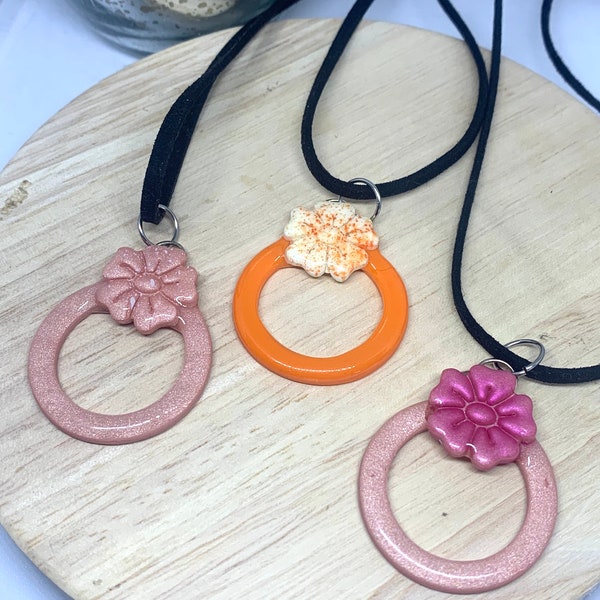 Collier cercle fleuris, trois modèles disponibles, rose moucheté, orange et rose fushia, monté sur une corde en daim noir, finition argent.