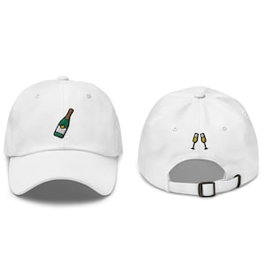 May include: White baseball cap with an embroidered champagne bottle on the front and two champagne glasses on the back.
