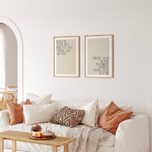 Könnte beinhalten: Zwei gerahmte Drucke mit beigefarbenem Hintergrund und schwarzem Text. Der Text auf dem linken Druck lautet "Isn't it just so pretty to think all along". Der Text auf dem rechten Druck lautet "There was some invisible string tying you to me".