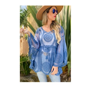 May include: A blue sheer top with embroidered lace detailing and a drawstring waist. The top has a V-neck and bell sleeves.
