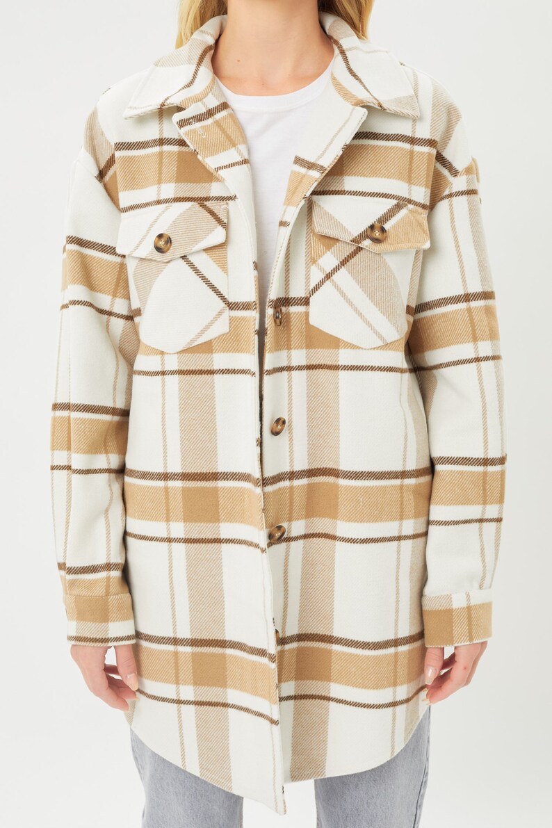 Puede incluir: Chaqueta de camisa a cuadros color crema con rayas marrones y beige. La chaqueta de manga larga tiene dos bolsillos delanteros con cierre de bot&oacute;n y una parte delantera abotonada. Tambi&eacute;n se ven el cuello y los pu&ntilde;os.