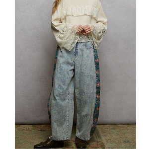 Puede incluir: Una blusa color crema con detalles de encaje y mangas acampanadas combinada con unos vaqueros de mezclilla con lavado ácido. Los vaqueros presentan paneles laterales con estampado floral. El conjunto es una mezcla de texturas y patrones, creando una estética bohemia única.