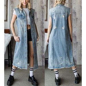 May include: A light blue denim vest with a distressed design. The vest is sleeveless and long, reaching the knees. It features a button-up front, pockets, and a frayed hem. The vest is worn over a white top and black shorts.