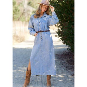 Könnte beinhalten: Ein hellblaues Jeanskleid mit langen Ärmeln, einer Knopfleiste und einem braunen Gürtel. Das Kleid hat einen hohen Schlitz und wird mit braunen Cowboy-Stiefeln und einem beigefarbenen Hut kombiniert. Das Kleid hat einen Vintage-Stil im Western-Look.