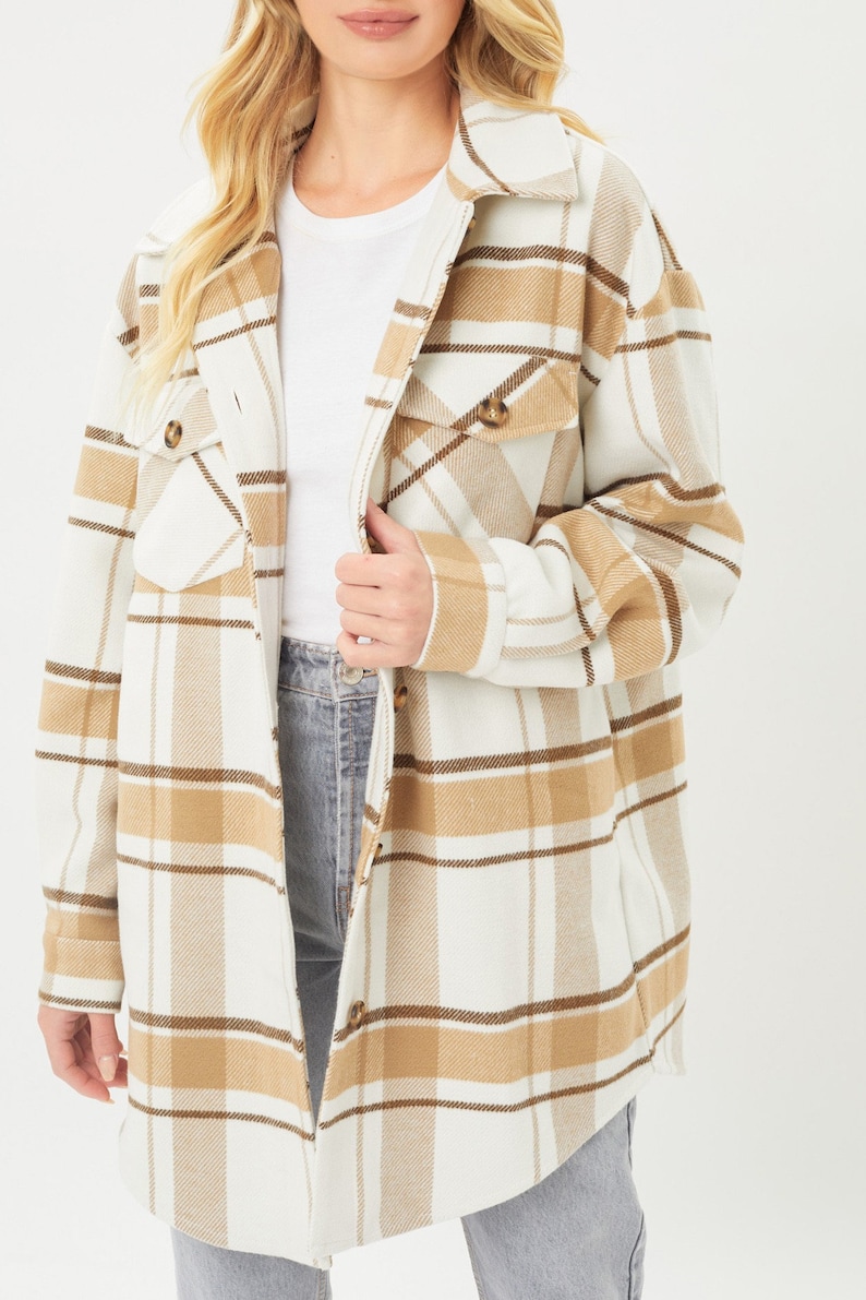 Puede incluir: Chaqueta larga a cuadros en crema, marr&oacute;n y beige. La chaqueta tiene cuello, botones y dos bolsillos delanteros. La modelo lleva una camiseta blanca y vaqueros azules.