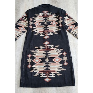 May include: A long, black cardigan sweater with a Southwestern-inspired geometric pattern in shades of brown, tan, and turquoise. The open-front design features long sleeves and a detailed design on the back.