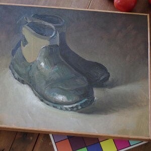 Pu&ograve; includere: Dipinto a olio di due stivali da lavoro verde scuro con finiture beige chiaro, su uno sfondo neutro. Gli stivali sono raffigurati in uno stile realistico, con trame e ombre visibili. L'opera d'arte &egrave; incorniciata in una cornice di legno marrone chiaro.