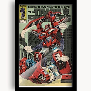 May include: Framed comic book art featuring Transformers characters in a battle scene. The artwork is in a vintage comic book style with bold colors and text bubbles. The title "More Than Meets The Eye" is visible.