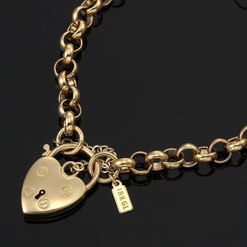 May include: A gold chain necklace with a heart-shaped padlock charm. The charm has a keyhole and the inscription "18KGL" on the tag.