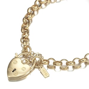 May include: A gold chain necklace with a heart-shaped padlock charm and a small tag that says "1BKG1".