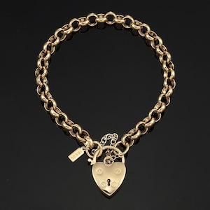 May include: A gold chain necklace with a heart-shaped padlock pendant. The padlock has a keyhole and is engraved with the word "Jewel".