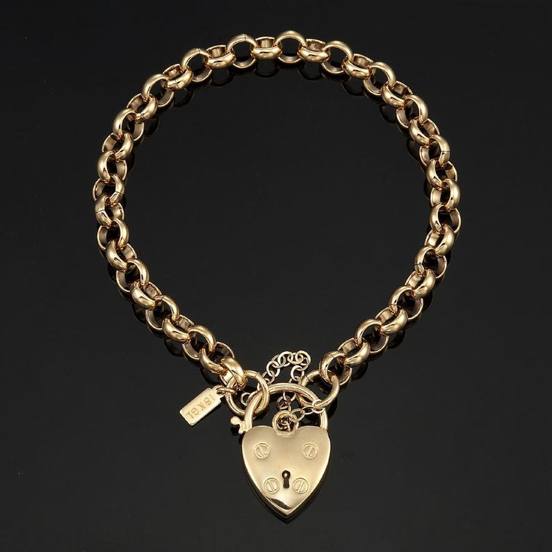 May include: A gold chain necklace with a heart-shaped padlock pendant. The padlock has a keyhole and is engraved with the word "Jewel".