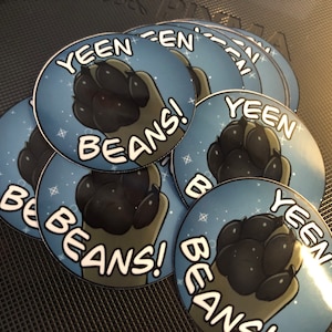 May include: A stack of round blue and white stickers with a black paw print and the text "YEEN BEANS!" printed on them.