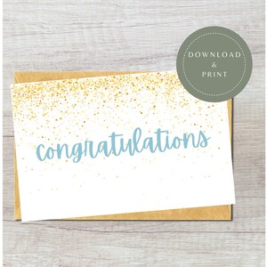 May include: A white card with a gold glitter background and the word "congratulations" written in light blue. The card is sitting on a brown envelope.