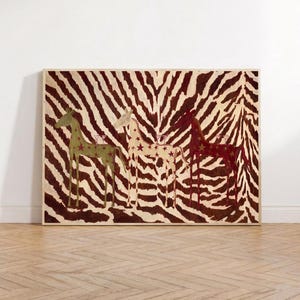 Puede incluir: Una pieza de arte mural rectangular enmarcada con un fondo de rayas de cebra en marr&oacute;n y crema. Tres figuras de jirafas estilizadas se sit&uacute;an en el centro, coloreadas en verde oliva, crema y rojo oscuro, decoradas con peque&ntilde;os patrones de estrellas.