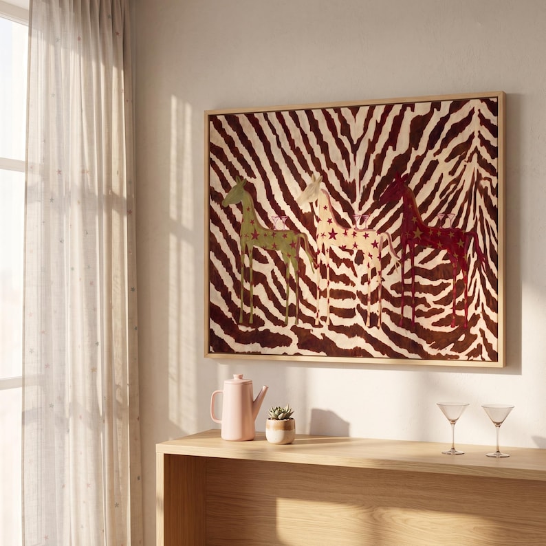 Puede incluir: Una pieza de arte mural rectangular enmarcada que presenta tres figuras de jirafas estilizadas en verde, crema y rojo oscuro, cada una decorada con peque&ntilde;as estrellas, sobre un fondo de rayas marrones y blancas de alto contraste.