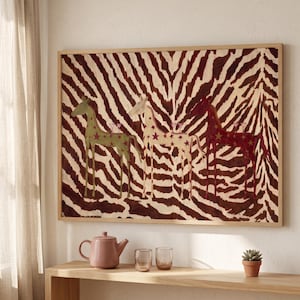 Puede incluir: Una pieza de arte mural rectangular enmarcada con un fondo de rayas de cebra marr&oacute;n y blanco, con tres figuras de caballos estilizadas en verde, crema y rojo oscuro, decoradas con estrellas y llevando un peque&ntilde;o vaso en el lomo.