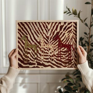 Puede incluir: Una impresi&oacute;n rectangular enmarcada con un fondo de rayas de cebra en marr&oacute;n y crema. Tres figuras de caballos estilizadas est&aacute;n dispuestas horizontalmente, coloreadas en verde oliva, crema y rojo oscuro, decoradas con peque&ntilde;as estrellas.