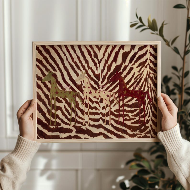 Puede incluir: Una impresi&oacute;n rectangular enmarcada con un fondo de rayas de cebra en marr&oacute;n y crema. Tres figuras de caballos estilizadas est&aacute;n dispuestas horizontalmente, coloreadas en verde oliva, crema y rojo oscuro, decoradas con peque&ntilde;as estrellas.