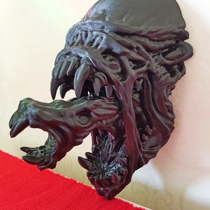 Könnte beinhalten: Eine schwarze 3D-gedruckte Skulptur einer Kreatur mit einem großen Maul und scharfen Zähnen. Der Kopf der Kreatur ist zur Seite geneigt, und sein Maul ist weit geöffnet, wodurch seine scharfen Zähne sichtbar werden. Die Skulptur ist aus glattem, schwarzem Kunststoff gefertigt.