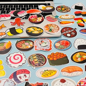 May include: A collection of colorful stickers featuring various Japanese food items, including sushi, ramen, and onigiri. The stickers are arranged in a grid pattern on a white surface.