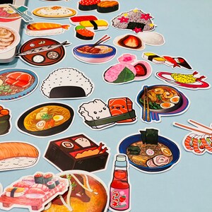 May include: A collection of colorful stickers featuring various Japanese food items, including sushi, ramen, and tempura. The stickers are arranged on a light blue surface.