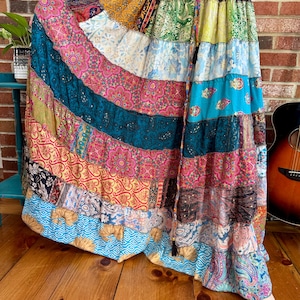 May include: A long, multi-colored patchwork skirt with a variety of floral and geometric patterns. The skirt is made of different fabrics and has a tiered design.