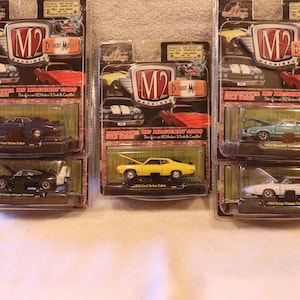 May include: Six die-cast model cars in their original packaging. The cars are various colors, including blue, yellow, black, and white. Each package features the "M2 Machines Detroit Muscle" logo and the model year and make of the car.