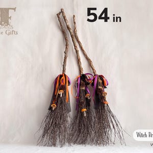 May include: Three decorative witch brooms measuring 54 inches in length. Each broom features a natural wooden handle, dark brown twig bristles, and is adorned with orange, purple, and black ribbons, small pinecones, and miniature mushroom accents.