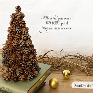 May include: A decorative pine cone tree, approximately 5.75 inches tall, crafted from 109 tiny and mini pine cones. The tree is brown and sits on a book. Two gold ornaments are nearby. The text reads "Decorative pine trees".