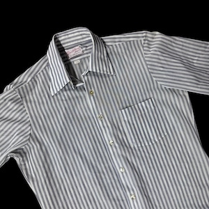 May include: A gray and white striped button-down shirt with a chest pocket. The shirt has a classic collar and long sleeves. The label reads "Decotone by D'Naples".