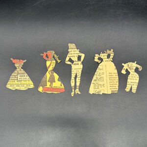 Puede incluir: Cinco recortes de papel vintage de siluetas de moda femenina. Los recortes est&aacute;n hechos de recortes de peri&oacute;dicos antiguos, con texto e ilustraciones. Las formas incluyen vestidos y una figura de pie, con acentos rojos y amarillos.