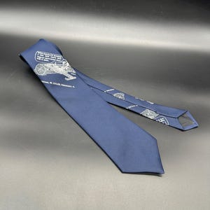 May include: A navy blue silk tie with a white print of a saw mill and the text "We had saw horses I saw new ones and they were so good they saw 4 more". The text also includes "Address: W. GILES, Chillicothe, O."