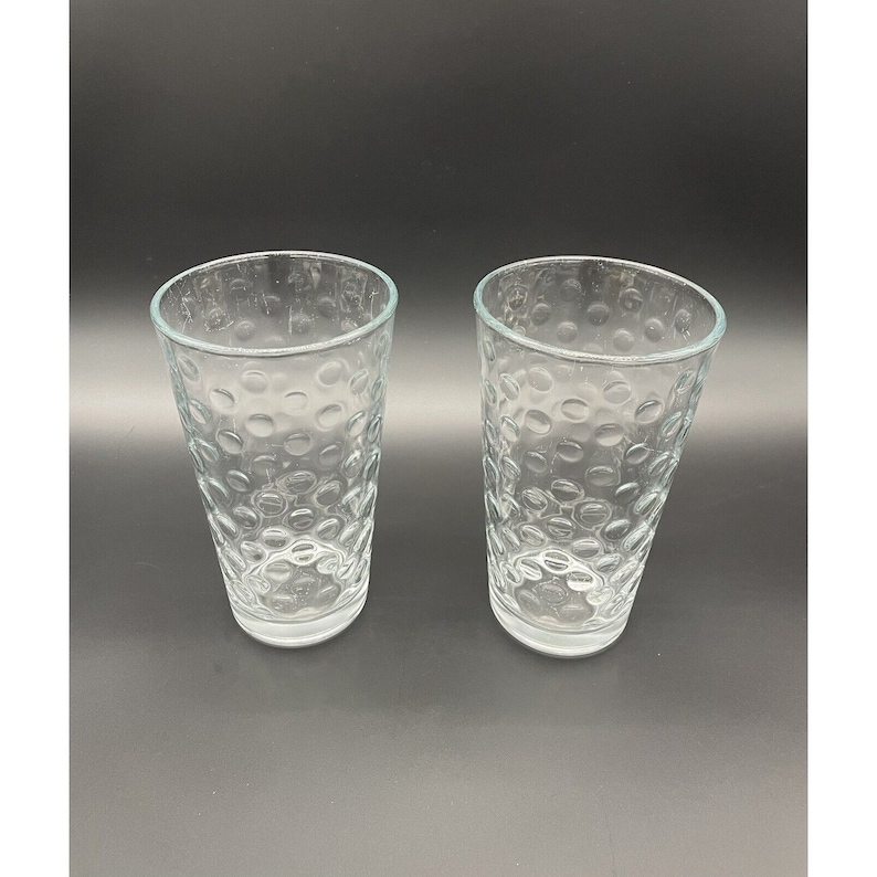 May include: Two clear glass drinking glasses with a textured, bubble-like pattern.