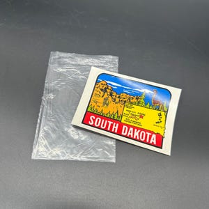 Calcomanía vintage de Dakota del Sur de los años 70 con mapa de lugares emblemáticos, dinosaurios, Monte Rushmore, viajes retro