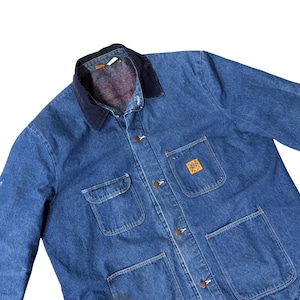 May include: A blue denim chore coat featuring a dark navy corduroy collar, metal button closures, and four front patch pockets. A square yellow patch with the text BIG BEN is stitched onto the upper left chest pocket area.