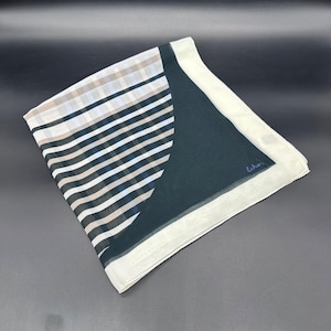 May include: A square scarf with a geometric design. The scarf features a combination of stripes and solid sections in white, black, blue, and tan. The edge is a solid white. The word "Echo" is written in blue in the corner.