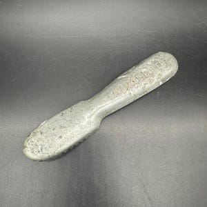 Puede incluir: Un raspador de hielo de metal plateado con un borde dentado y el texto "ICE SCRAPER" grabado en el mango.