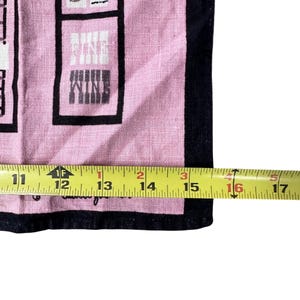 Pu&ograve; includere: Canovaccio da cucina rosa e nero a tema vino. Il canovaccio presenta la parola "WINE" in un design a blocchi. Il canovaccio misura circa 40,6 cm di lunghezza.